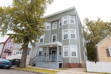 New Haven apartment for rent - A grey two-story house with a balcony and a tree in front.