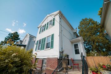 New Haven apartment for rent - A white house with green shutters and a red chair on the porch.