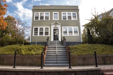 New Haven apartment for rent - A grey building with a black door and steps leading up to it.