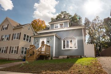 New Haven apartment for rent - A house with a grey front and a white door is surrounded by trees.