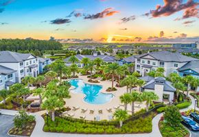 Orlando apartment for rent - an aerial view of a large swimming pool with palm trees and buildings around it