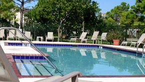 Deerfield Beach apartment for rent - a swimming pool with chairs and trees in the background