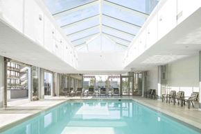 Stamford apartment for rent - the pool is under a large glass roof in therium of a building with chairs