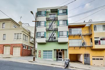 San Francisco apartment for rent - A street view of a residential area with buildings and a motorcycle parked on the sidewalk.