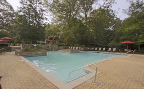 Stone Mountain apartment for rent - A large outdoor swimming pool surrounded by trees and lounge chairs.