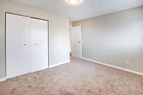 High River apartment for rent - an empty bedroom with white closet doors and carpeting