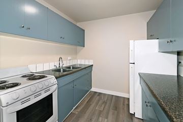Edmonton apartment for rent - A kitchen with a white stove and blue cabinets.