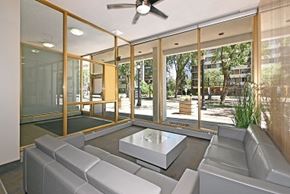 Edmonton apartment for rent - A modern living room with a glass wall and a ceiling fan.