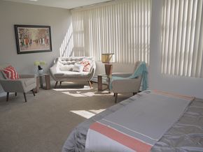 Edmonton apartment for rent - a bedroom with a bed and two chairs and a window with vertical blinds
