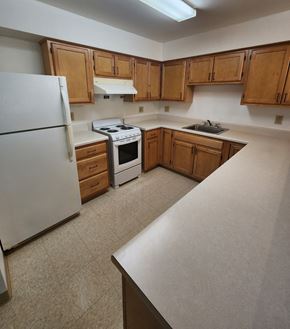 Rochester apartment for rent - A kitchen with white appliances and wooden cabinets.
