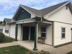 Farmington townhouse for rent - A small white building with a green door and a bench outside.