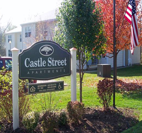 Rushville apartment for rent - a castle street apartments sign in front of a yard with two flags