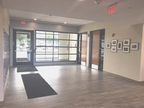 Rochester apartment for rent - an empty hallway with doors and a black rug and paintings on the wall