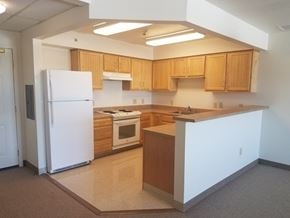 Rochester apartment for rent - an empty kitchen with white appliances and wooden cabinets