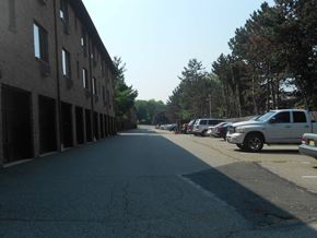 Mahwah apartment for rent - A long, empty street with cars parked on the side and a building on the left.