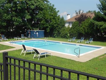Mahwah apartment for rent - A pool surrounded by lawn chairs and trees.