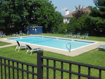 Mahwah apartment for rent - A pool surrounded by lawn chairs and a fence.