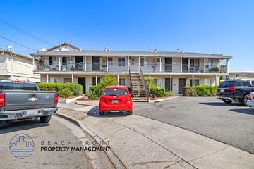 Anaheim apartment for rent - a parking lot with a red car in front of an apartment building