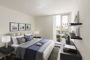 Calgary apartment for rent - bedroom with large window, bed, and lamp
