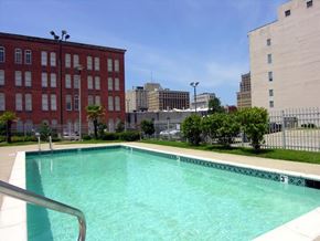 Shreveport apartment for rent - A swimming pool in front of a red brick building with a number 3 on the side.