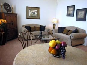 Shreveport apartment for rent - A living room with a couch, chairs, a coffee table, and a vase of fruit on the table.