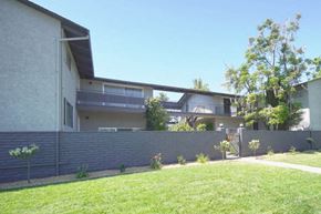 Palo Alto apartment for rent - A modern house with a grey wall and a green lawn in front.