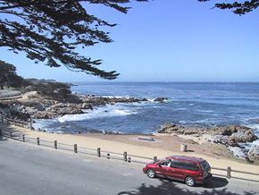 Pacific Grove apartment for rent - A red car is parked on the side of a road near the beach.