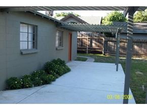 Modesto house for rent - A house with a grey wall and a brown door.