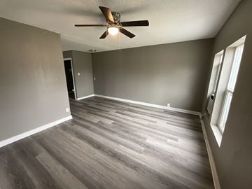Abilene apartment for rent - A room with a ceiling fan and wooden flooring.