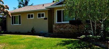 San Jose house for rent - A house with a brown and beige exterior and a green lawn in front.