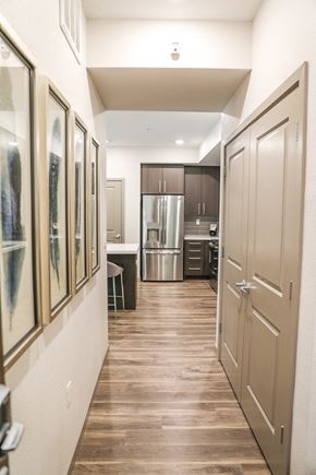 Sacramento apartment for rent - a hallway leading to a kitchen with a stainless steel refrigerator and