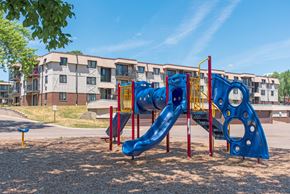 West Saint Paul apartment for rent - a playground with a blue slide in front of an apartment building