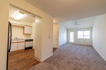 Carpeted living room and view of kitchen