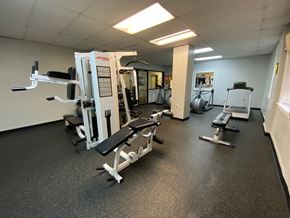 Chicago apartment for rent - A gym with a variety of equipment including a squat rack, a leg press machine, and a bench press.