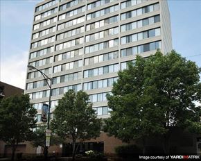 Chicago apartment for rent - A tall building with many windows is surrounded by trees.