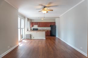 Chicago apartment for rent - an empty living room with a ceiling fan and a kitchen