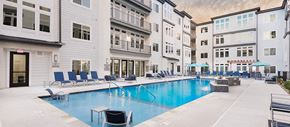 Kansas City apartment for rent - a swimming pool with chairs and umbrellas in front of a building