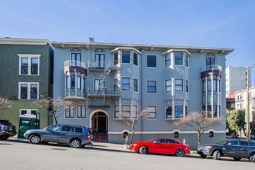 San Francisco apartment for rent - A grey building with a red car parked in front.