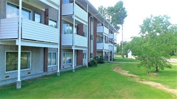 Thompson apartment for rent - a row of buildings with grass and trees in front of them