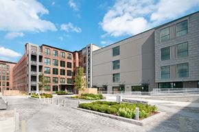 Lowell apartment for rent - A modern building complex with a cobblestone walkway in front.