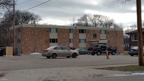 Moorhead apartment for rent - A car is parked in front of a brick building.