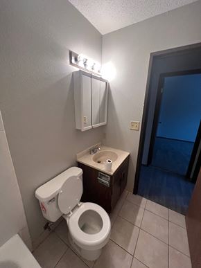 Moorhead apartment for rent - A white toilet with a white tank and a white toilet paper roll on top of a brown sink.