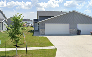West Fargo house for rent - A tree stands in front of a house with a garage door.