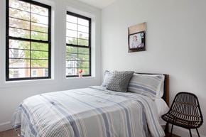 Brooklyn apartment for rent - A bedroom with a bed, pillows, a chair, and a picture on the wall.
