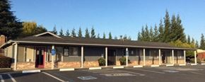 Modesto apartment for rent - the front of a building with a parking lot and trees