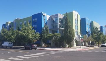 Reno apartment for rent - A street view of a modern building with cars and trees.
