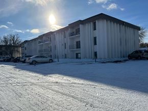Moorhead apartment for rent - A sunny day in a snowy parking lot with a large white building in the background.