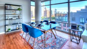 Chicago apartment for rent - A glass-top dining set sits before floor-to-ceiling windows that show a number of Chicago buildings in the distance.