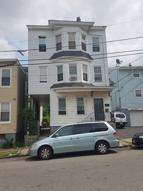 Paterson apartment for rent - A blue car is parked in front of a two-story house.