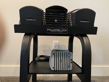 A black powerblock weight bench with weights on the seat.